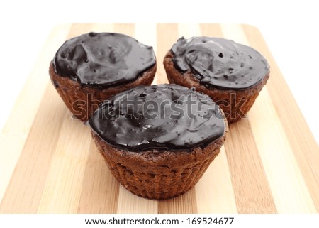 Closeup of fresh baked muffin with cacao and chocolate on chopping board. Isolated on white background