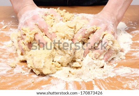 Hand of woman kneading dough for yeast cake on wooden table, preparing yeast cake