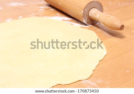 Sheeted yeast cake and rolling pin lying on wooden table, preparing yeast cake