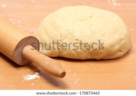 Yeast cake and rolling pin lying on wooden table, preparing yeast cake