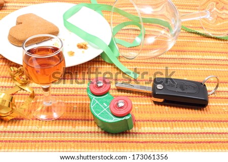 Closeup of car key and overturned model vehicle with glass of wine lying on table after party, car key and alcohol, don\'t drink and drive concept