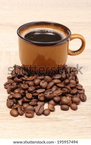 Heap of coffee grains and cup of hot beverage, cup of coffee. Isolated on wooden background