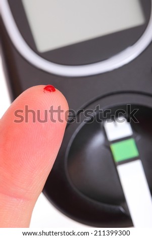 Closeup of finger with blood and glucose meter, taking blood sample from finger, measuring sugar level