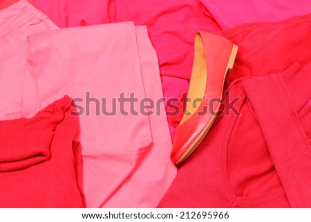 Heap of red and pink shirts and pants with womanly shoes, womanly clothes