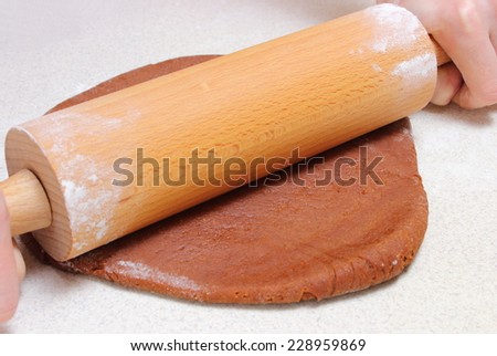 Hands of woman with rolling pin kneading dough for Christmas cookies