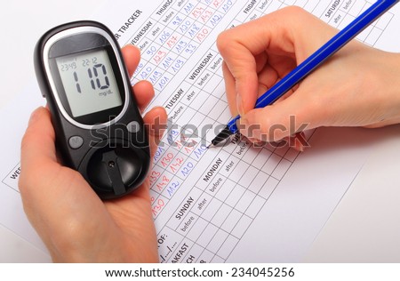 Hand of woman writing data from glucometer to medical form, result of measurement sugar, concept for measuring sugar level