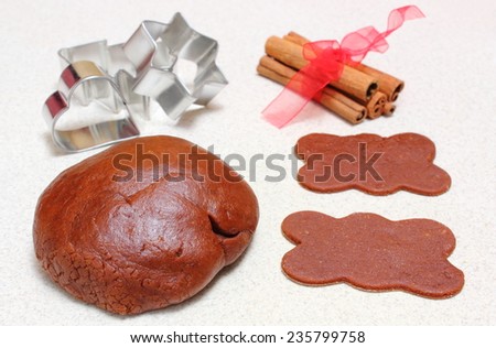 Homemade gingerbread dough for Christmas cookies, cinnamon sticks and cookie cutters on kitchen table