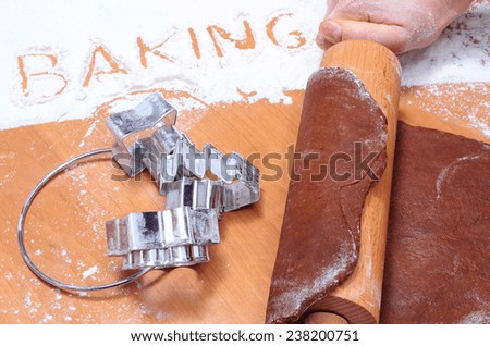 Hand of woman with rolling pin kneading dough for Christmas cookies and gingerbread, set of cookie cutters, concept for baking
