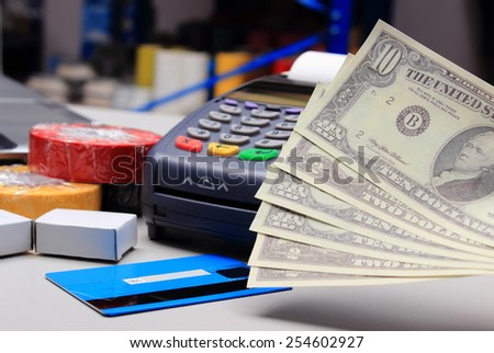 Money and payment terminal with credit card in an electrical shop, paying for shopping, finance concept