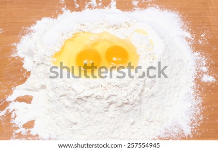 Heap of wheat flour and broken egg, baking ingredients, preparing yeast cake