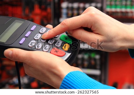 Hand of woman using payment terminal in an electrical shop, enter personal identification number, finance concept