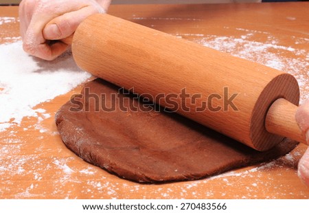 Hand of woman with rolling pin kneading dough for cookies, concept for baking