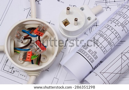 Copper wire connections in electrical box, rolls of electrical diagrams and electric plug on construction drawing of house, accessories for engineering work, energy concept