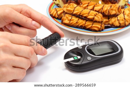 Woman doing test for level sugar, glucose meter and fresh baked pastry on colorful plate in background, concept for diabetes and glucose level test