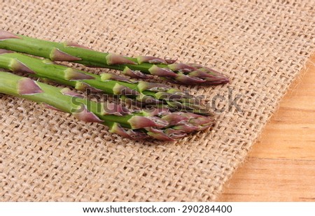 Fresh green asparagus on burlap bag, concept of healthy food, nutrition and strengthening immunity. Wooden background