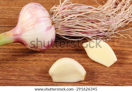 Fresh whole garlic with roots and cloves on wooden surface, healthy food and nutrition