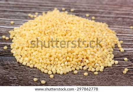 Heap of yellow millet groats on wooden background, concept for healthy eating and nutrition