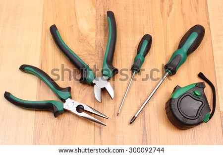 Metal pliers, electrical screwdrivers and tape measure on wooden surface, work tools and accessories for engineering jobs