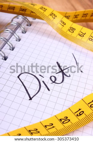 Tape measure lying on notebook for writing notes, concept of slimming and diet