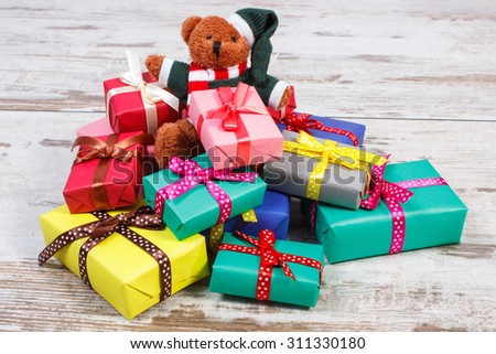 Fluffy teddy bear and heap of wrapped colorful gifts for Christmas, birthday, valentines or other celebration on old wooden white table