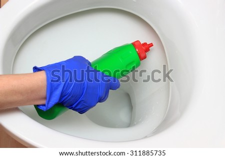 Hand of woman in blue glove cleaning toilet bowl using detergent, concept for house cleaning and household duties