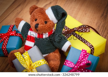 Fluffy teddy bear and heap of wrapped colorful gifts for Christmas, birthday, valentines or other celebration on wooden plank