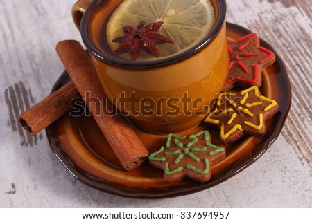 Cup of hot tea, fresh baked homemade decorated gingerbread or Christmas cookies, cinnamon sticks on old white wooden background, christmas time