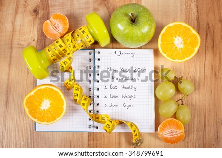 New years resolutions eat healthy, lose weight and join gym written in notebook, dumbbells for fitness with tape measure, concept of healthy lifestyle