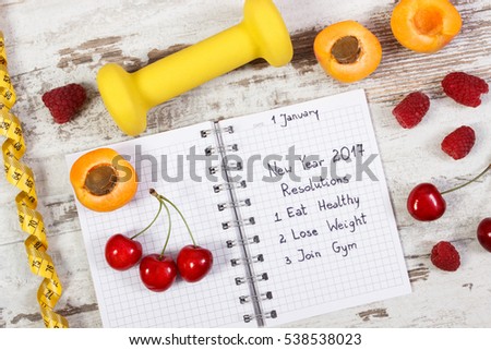 New year resolutions or goals eat healthy, lose weight and join gym written in notebook, fresh fruits, dumbbells for fitness and tape measure