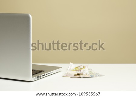 Open Laptop on white desk with money