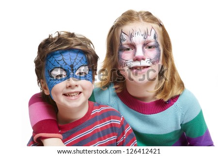 Young boy and girl with face painting of cat and superhero smiling on white background