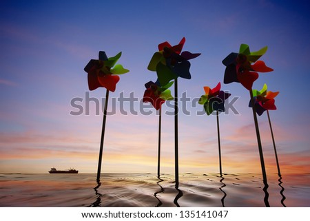 Toy windmill concept of green energy wind farm at sea with sunset
