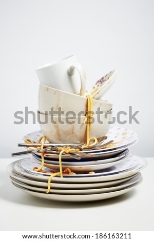 Dirty dishes pile needing washing up. Household chore concept on white background