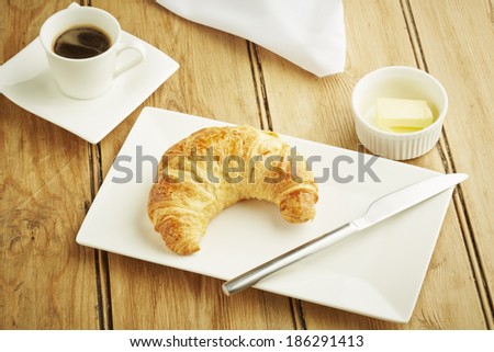 Croissant pastry on white dish and wooden table top