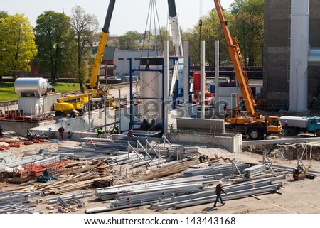 Construction site view of modern biomass co generation plant with people, cranes and construction materials on it