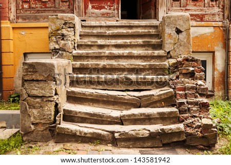 Old partially with the time destroyed staircase leading to a house door