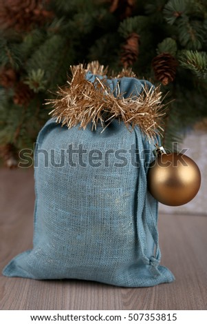Soft blue Santa bag in Christmas time. Woven linen fabric pouch. Gifts bag decorated with gold ball.