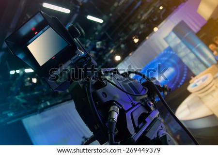 Television studio with camera and lights - recording TV show. Shallow depth of field - focus on camera