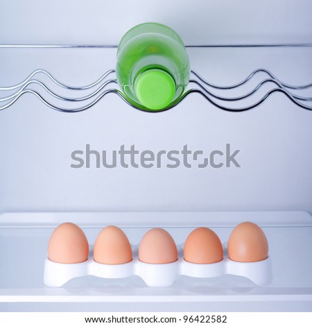 Inside the fridge are five eggs and a bottle of milk