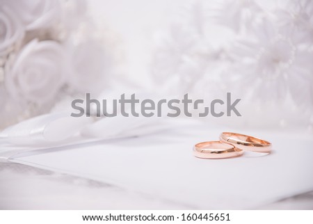 The wedding invitation with wedding rings and a bouquet of the bride on a white backgroundThe wedding invitation with wedding rings and a bouquet of the bride on a white background
