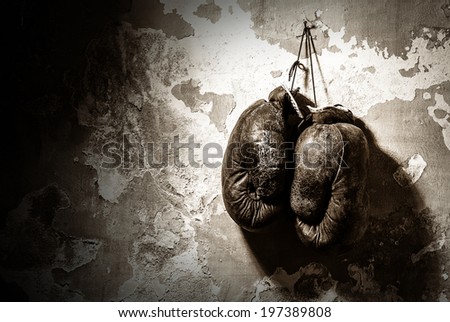 old boxing gloves hang on nail on texture wall