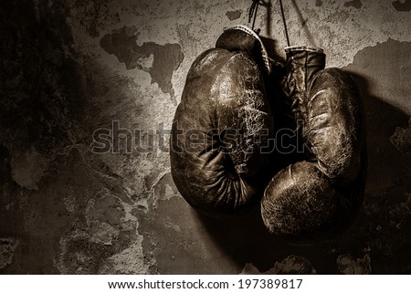 old boxing gloves hang on nail on texture wall
