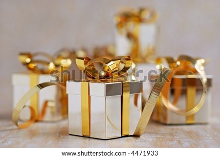 miniature silver and gold gift box ornaments on sweep of gift wrap with shallow dof