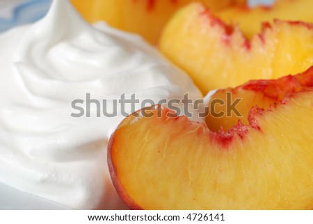Peaches and Cream.  Closeup of freshly sliced peaches with whipped topping on light blue plate.  Shallow dof