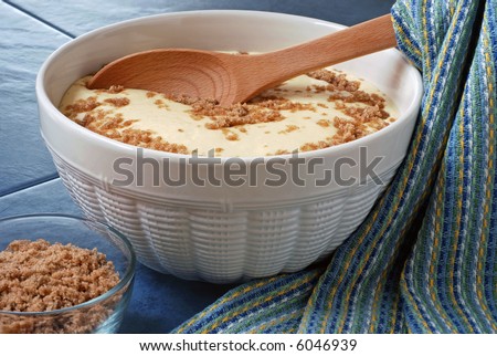 Bowl of homemade pancake batter and cinnamon streusel mix with wooden spoon on a blue tile background.