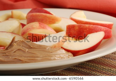 Close-up of freshly sliced apples and peanut butter on plate with color coordinated napkin as background.  Shallow dof