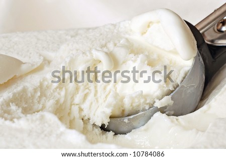 Vanilla ice cream with serving scoop against a cream colored background.  Macro with shallow dof.
