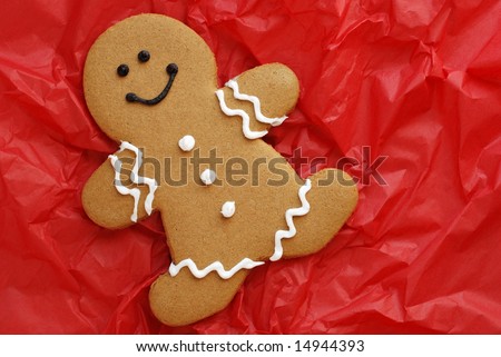 Smiling gingerbread man on crumpled, red tissue paper.