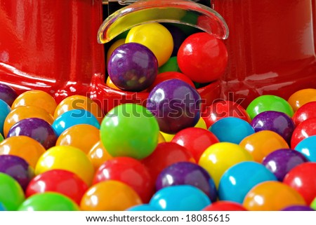 Colorful bubble gum spilling from a gumball machine.  Macro with shallow dof.  Selective focus on dispenser opening.
