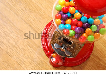Colorful bubble gum in gumball machine with wood grain background.  Close-up with shallow dof.  Copy space included.
